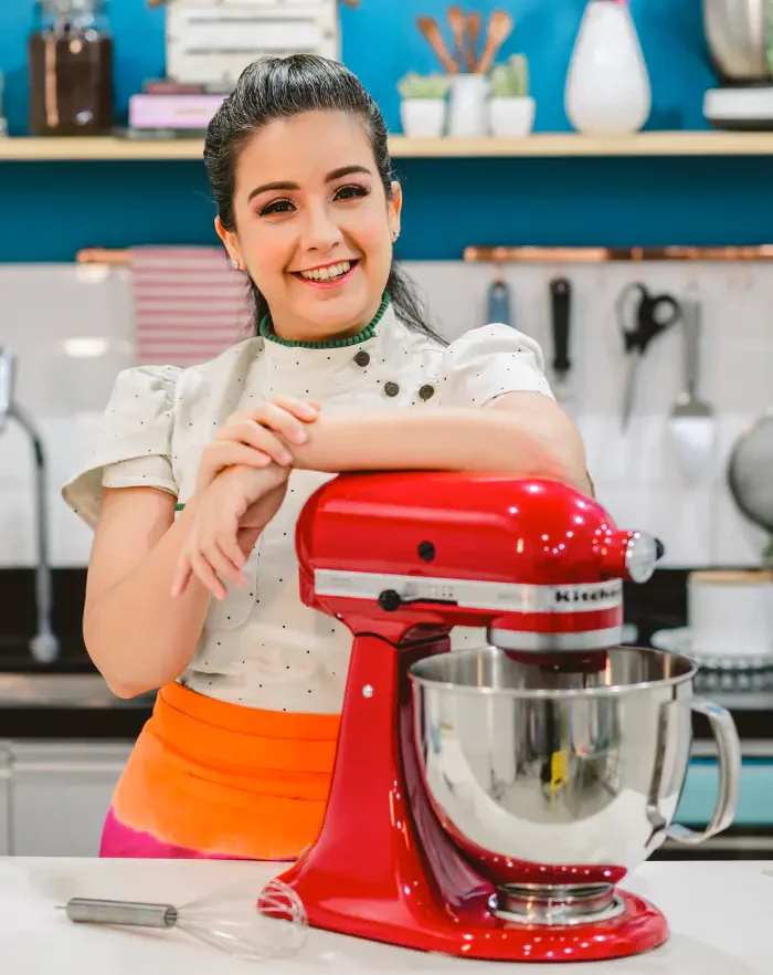 Dani Dias em seu ateliê, sorrindo ao lado de sua batedeira